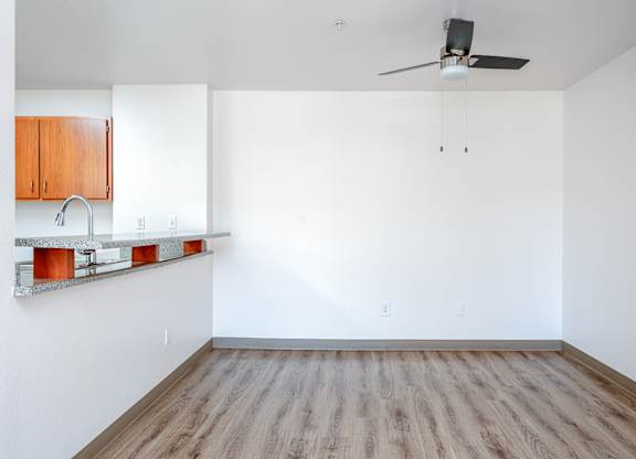 Empty room with wooden floor and ceiling fan.