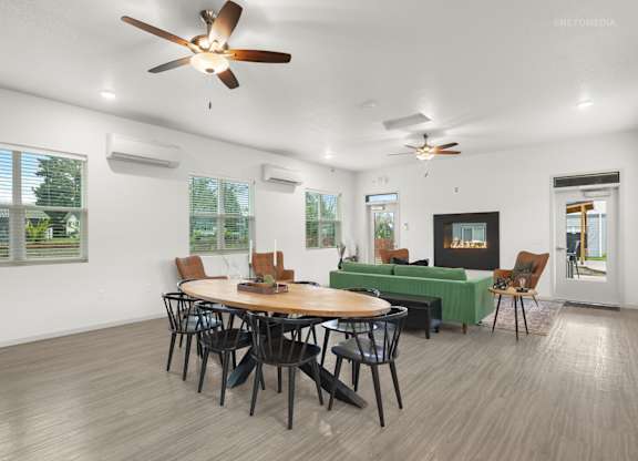 A room with a table and chairs and a ceiling fan.