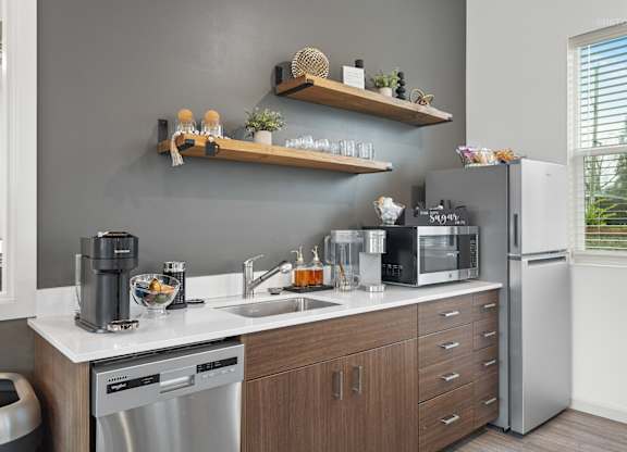 A modern kitchen with a grey wall and wooden shelves.