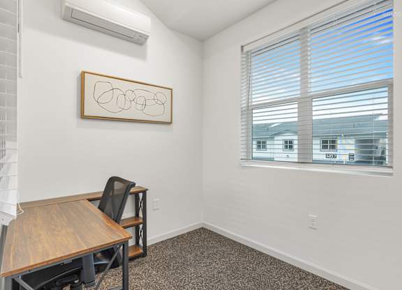 A room with a table and a window with blinds.