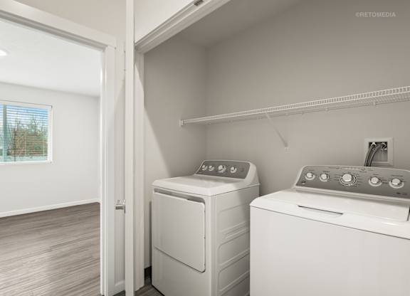 A white dryer and washer are sitting next to each other in a small laundry room.