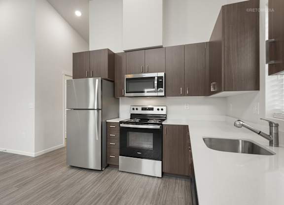A modern kitchen with a stainless steel refrigerator, microwave, oven, and sink.