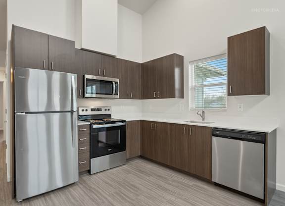 A modern kitchen with a stainless steel refrigerator, microwave, oven, and dishwasher.