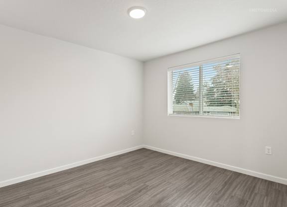 A room with a window showing trees outside.