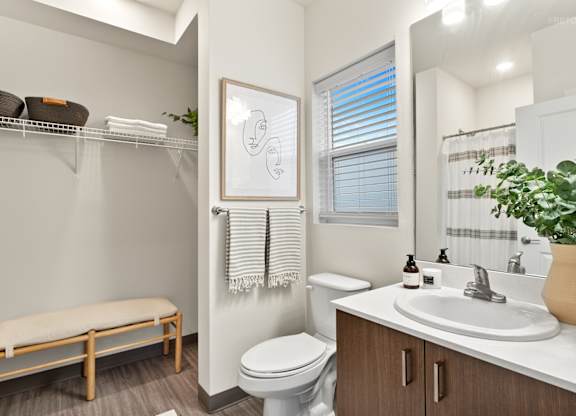 A bathroom with a toilet, sink, and a window with blinds.