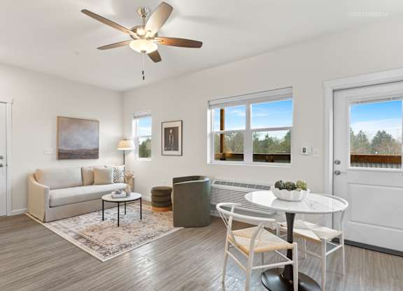 A living room with a white couch, a white coffee table, and a ceiling fan.