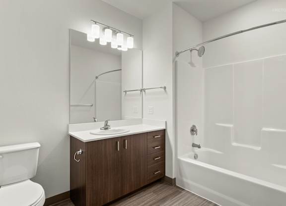 A bathroom with a white tub, sink, and toilet.