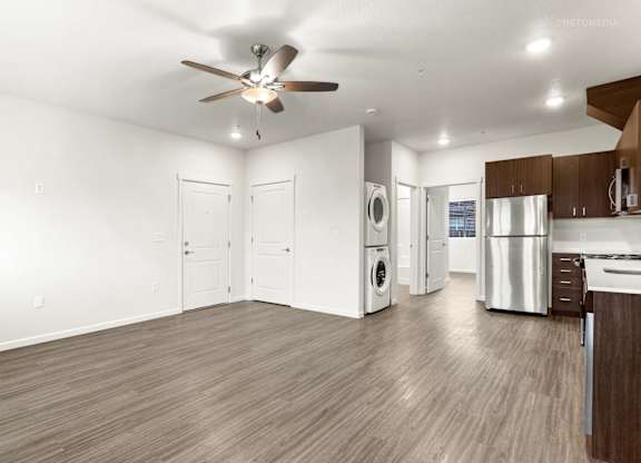A spacious kitchen and living room with wood flooring and white walls.