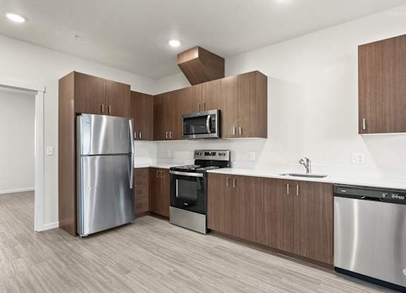 A modern kitchen with a stainless steel refrigerator, microwave, oven, and dishwasher.