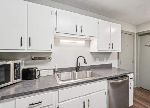 A kitchen with white cabinets and a stainless steel dishwasher.