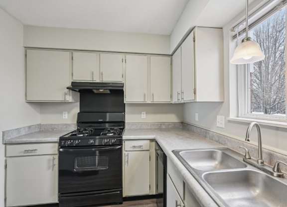 A kitchen with a black stove top oven and white cabinets.