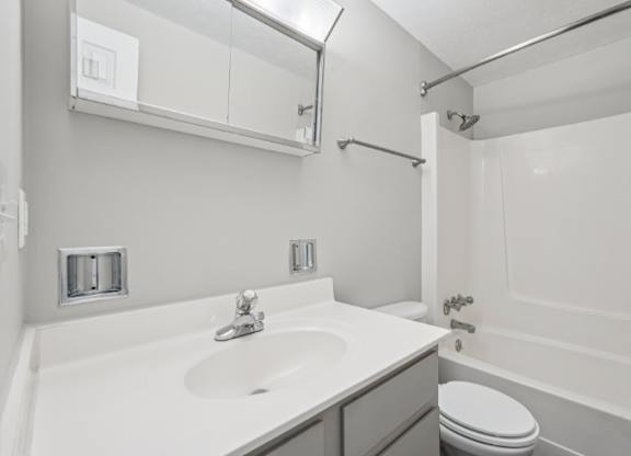 A white bathroom with a sink, toilet, and bathtub.