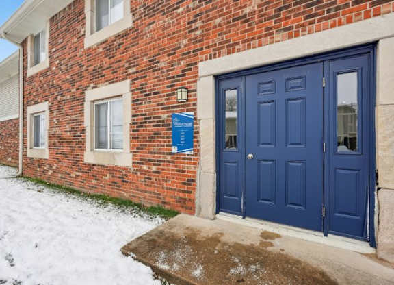 A red brick building with a blue door and a blue sign on the wall.