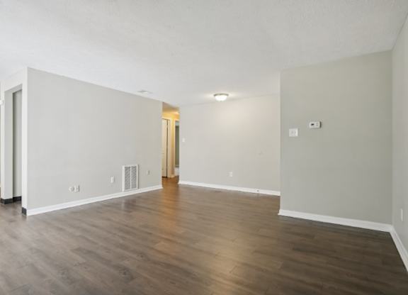 A large empty room with wooden floors and white walls.