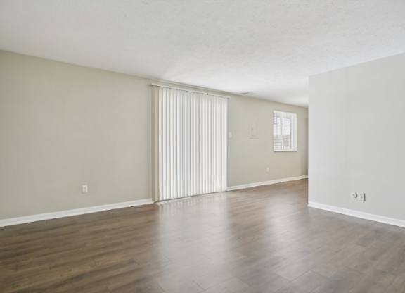 A room with wooden floors and a window with blinds.
