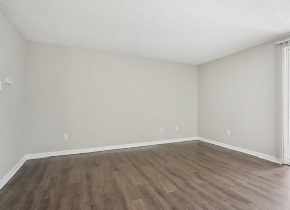 A room with wooden flooring and a window with bars on it.