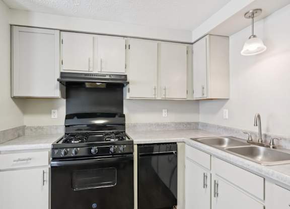 A black stove top oven sits in a kitchen with white cabinets.