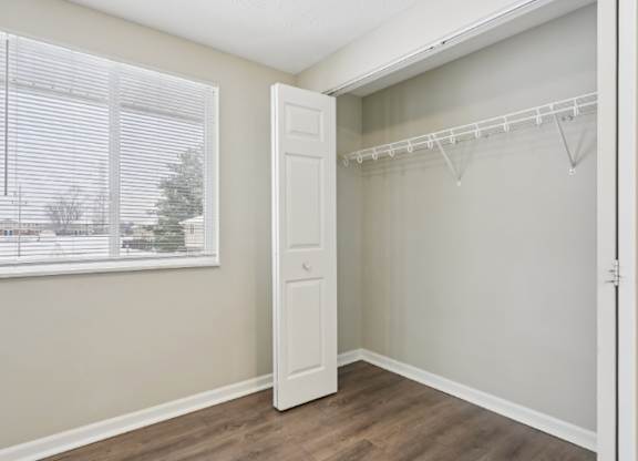 A room with a white door and a window with blinds.