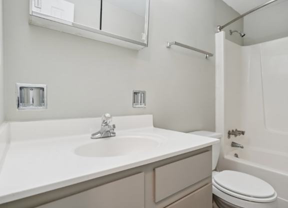 A white sink in a bathroom with a toilet and a shower.