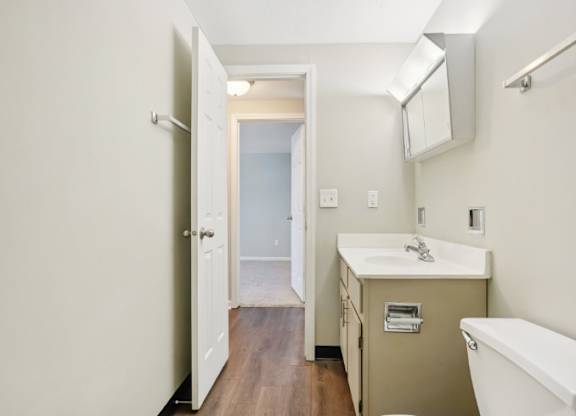 A bathroom with a white tub, sink, and wooden floor.