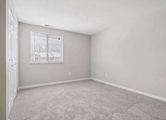A room with a carpeted floor and a window.