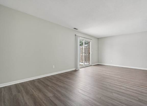 A room with a wooden floor and a door leading to a balcony.