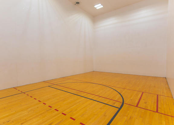 A squash court with a yellow floor and white walls.