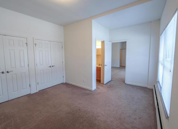 A room with white doors and carpeted floor.