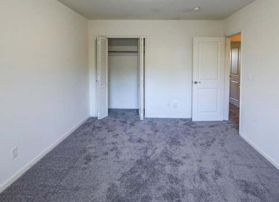 A room with a grey carpet and white walls.