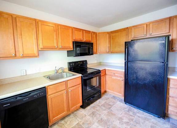 A kitchen with black appliances and wooden cabinets.