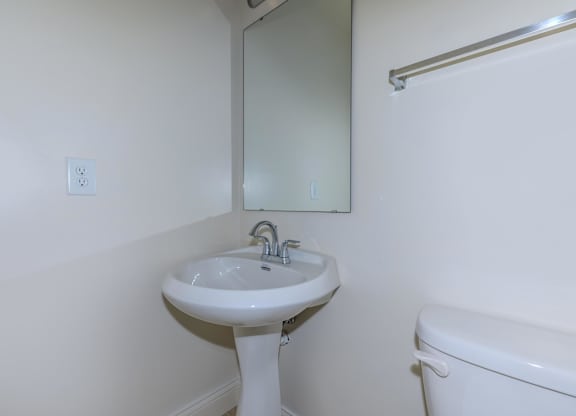 A white pedestal sink with a mirror above it.