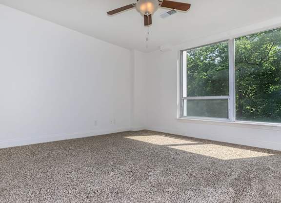 A room with a ceiling fan and a window.