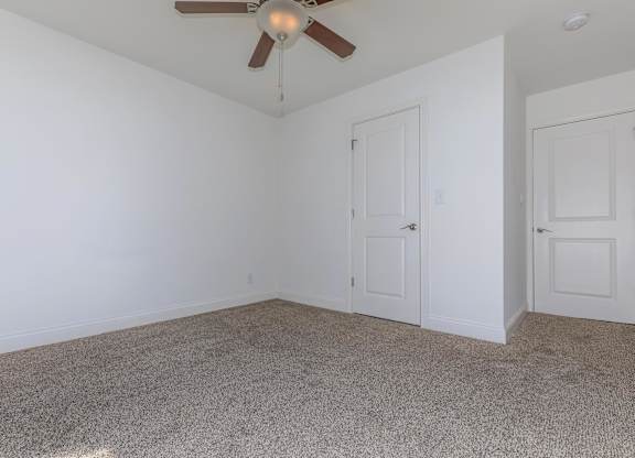 A room with a ceiling fan and carpeted floor.