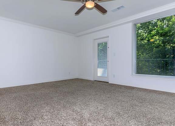 A room with a ceiling fan and carpeted floor.