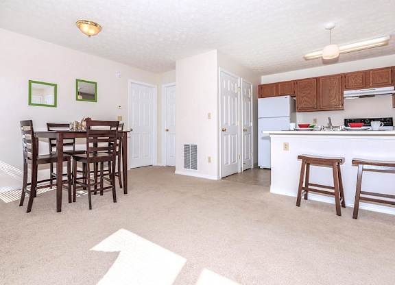 A kitchen with white appliances and brown wooden bar stools.