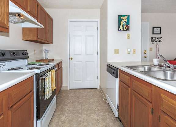 A kitchen with a white door and brown cabinets.