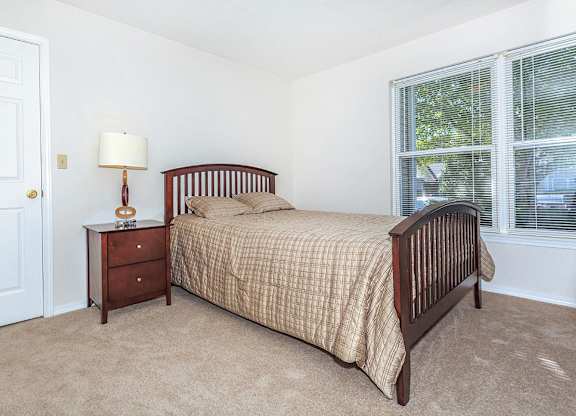 A bedroom with a bed, nightstand, and window.