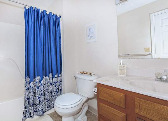 A white toilet with a blue shower curtain in a bathroom.