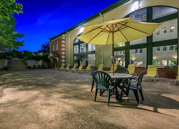 A yellow umbrella is on a table outside a building.