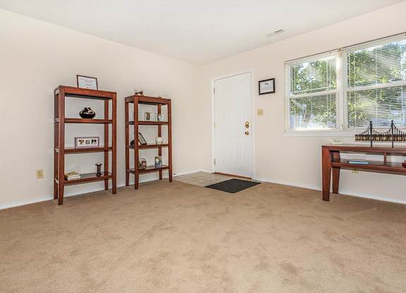 A room with a carpeted floor and a window with blinds.
