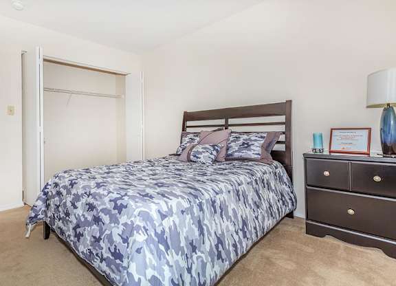 A bedroom with a bed, nightstand, and lamp.