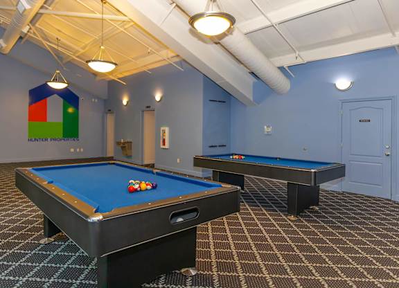 A pool table with a blue cloth and a pool table with a brown cloth.