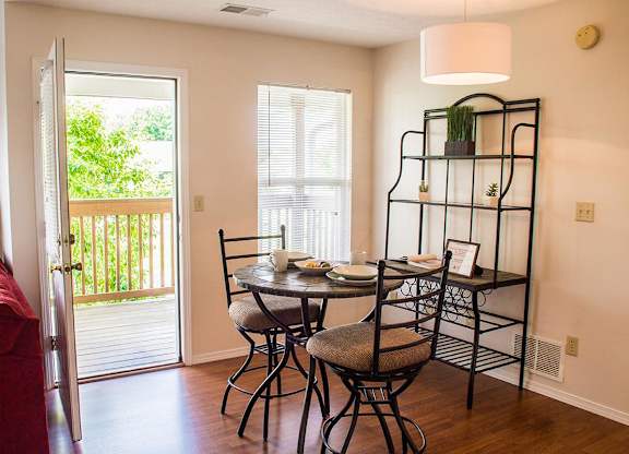 A dining room with a table set for two and a red couch.