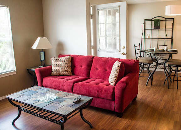 A red couch with a glass table in front of it.