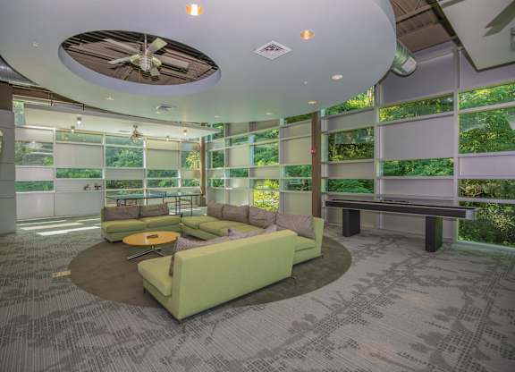A room with a green couch and a ceiling fan.
