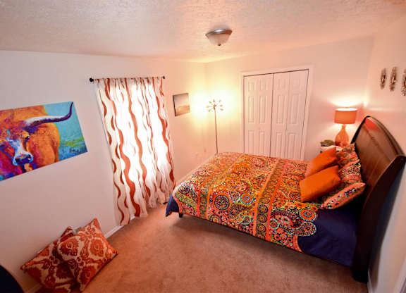 A bedroom with a bed, pillows, and a painting on the wall.