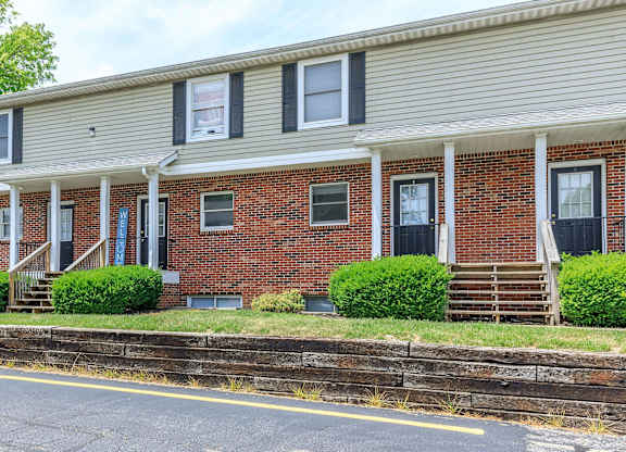 A red brick house with a porch and a white roof.