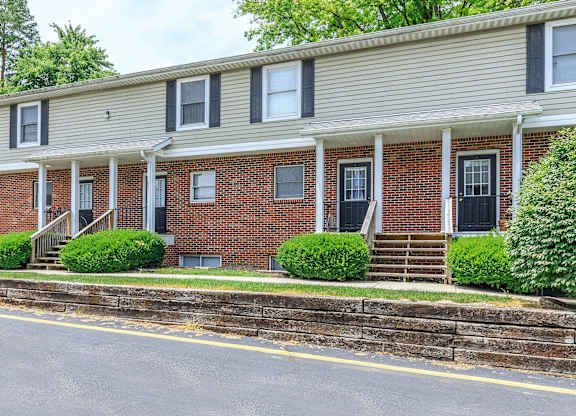 A row of red brick houses with white trim and black shutters.
