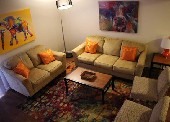 A living room with a couch, chair, and a painting on the wall.