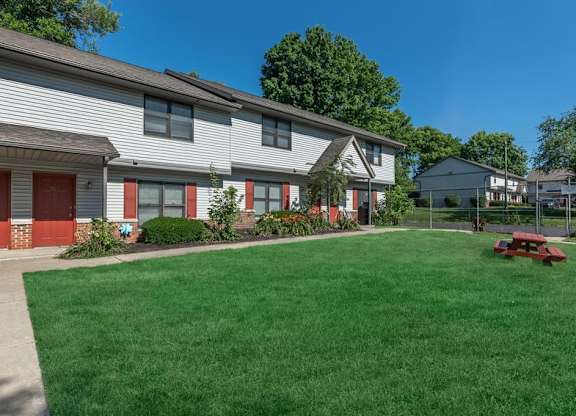 A house with a red garage door and a green lawn.